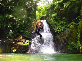 西表島コロンブスが行うシーカヤック＆シャワートレッキング＆キャニオニングツアーでの一コマで、西表島の奥地にある滝の前からジャンプしているツアー写真を撮影。